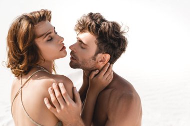 Kumsalda kucaklaşan tutkulu seksi genç çift. 