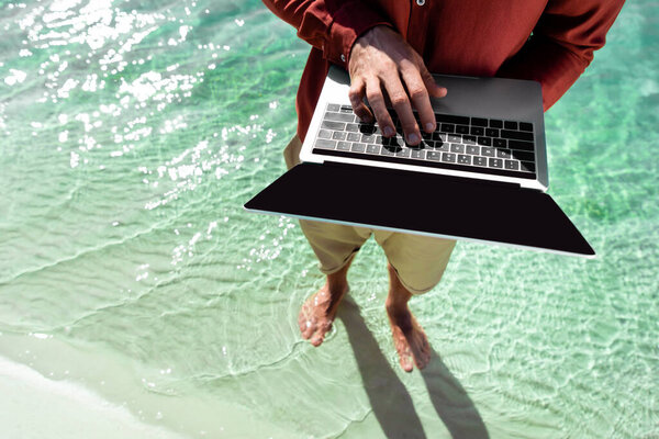 top view of freelancer with laptop standing in turquoise water