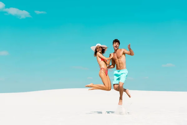 Sorrindo Jovem Casal Pulando Juntos Praia Areia — Fotografia de Stock