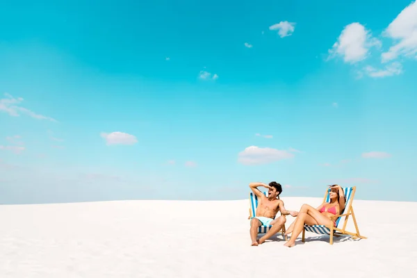 若いカップルがデッキチェアに座って砂浜を眺めながら — ストック写真