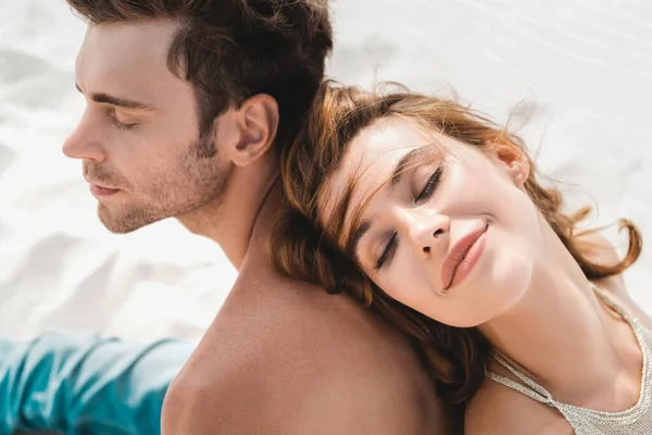 Sorridente Giovane Coppia Seduta Schiena Schiena Sulla Spiaggia — Foto Stock