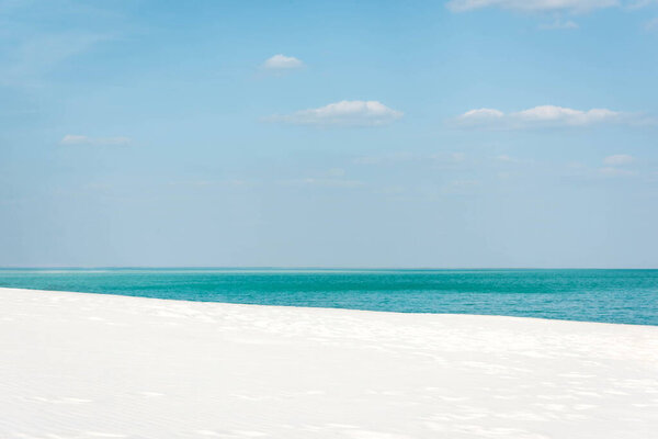 beautiful beach with turquoise ocean, white sand and blue sky with white clouds