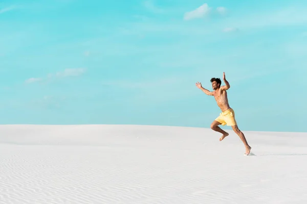 身穿泳裤 肌肉发达的男子在沙滩上奔跑 — 图库照片