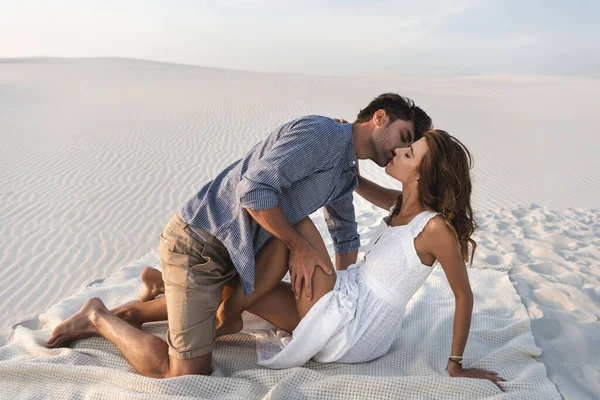 热情的年轻夫妇在海滩的毛毯上接吻 — 图库照片