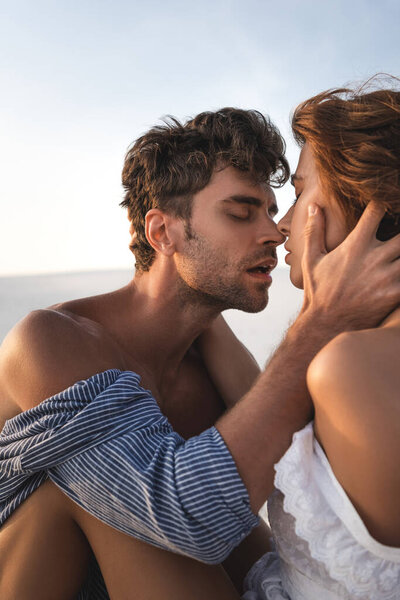 страстная молодая пара целуется на пляже
