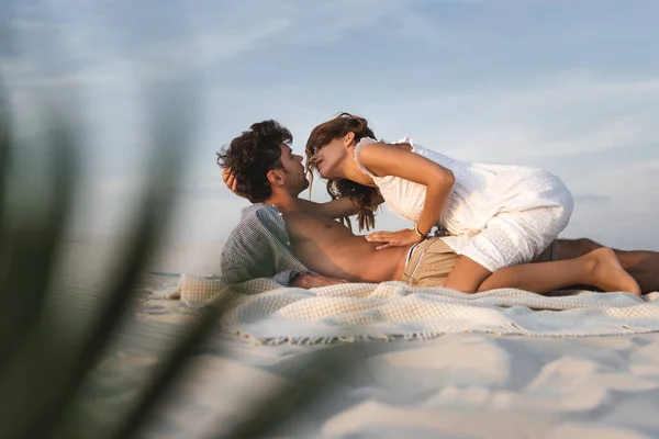 有选择性地聚焦在有激情的年轻女子坐在沙滩上的男友身上 — 图库照片