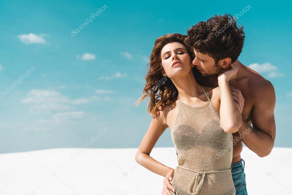 young man kissing passionate sexy young girlfriend on beach 