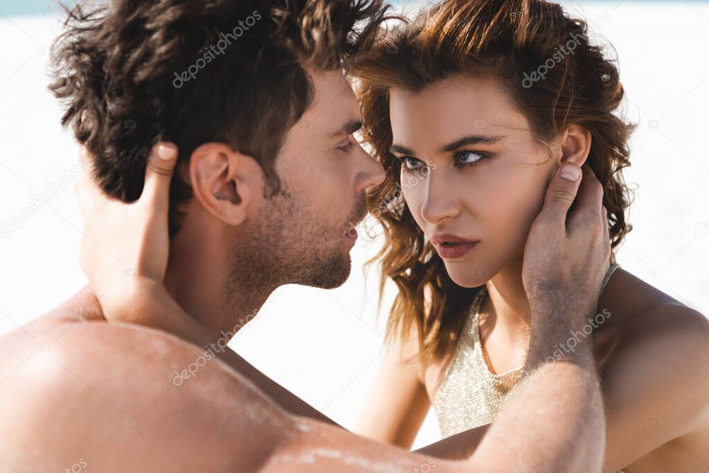 passionate sexy young couple looking at each other on beach 