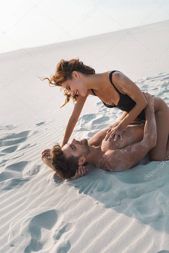 happy sexy passionate young couple lying on sandy beach 