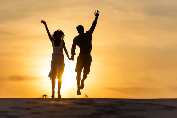 Silhuetter Man Och Kvinna Hoppar Stranden Mot Solen Solnedgången — Stockfoto