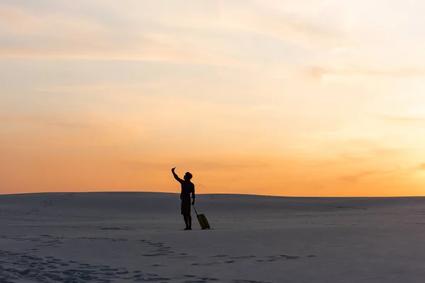 Silhouette Eines Mannes Der Bei Sonnenuntergang Mit Reisetasche Und Smartphone — Stockfoto