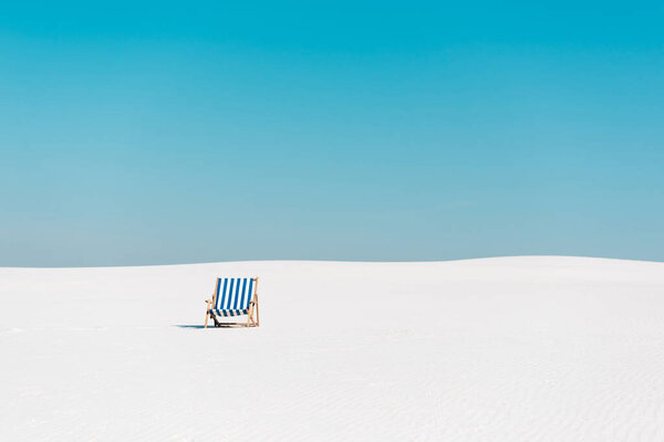 пустой шезлонг на песчаном пляже против ясного голубого неба
