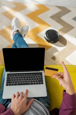 Robotik elektrikli süpürge oturma odasında halı yıkarken internetten insan alışveriş görüntüsü.