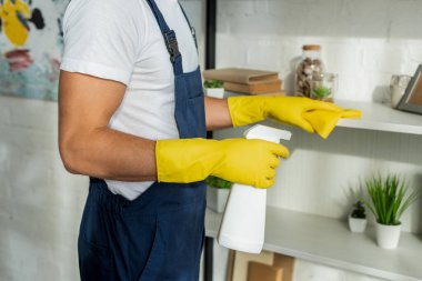 Apartmandaki rafları temizleyen önlüklü temizlikçi manzarası 