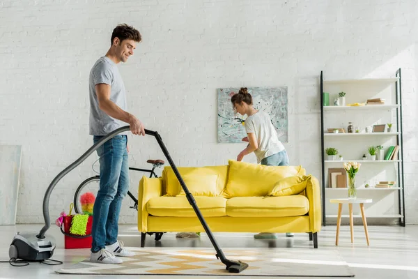 Pria Bahagia Menggunakan Vacuum Cleaner Dekat Wanita Ruang Tamu — Stok Foto