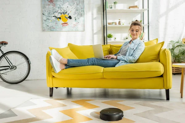 Happy Woman Using Laptop While Robotic Vacuum Cleaner Washing Carpet — Stock Photo, Image