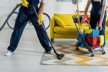 cropped view of cleaners in overalls cleaning apartment  clipart
