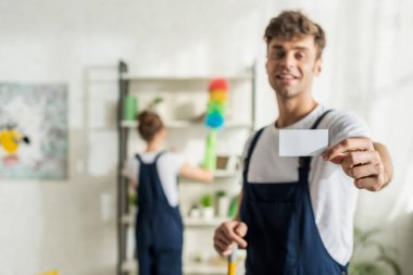 Mutlu ve yakışıklı temizleyicinin seçici odak noktası boş kart tutuyor 