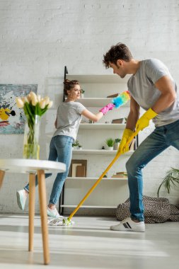 Bir kadının dairede bahar temizliği yaparken yakışıklı bir adama bakması. 