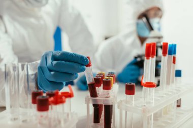 Biyokimyacının, meslektaşının yanında kan örneğiyle test tüpü alırken kısmi görüntüsü