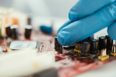 Bilgisayar anakartının yanındaki lastik eldivenli mühendisin seçici odak noktası