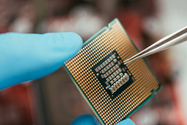 close up view of computer microchip and tweezers in hands of engineer