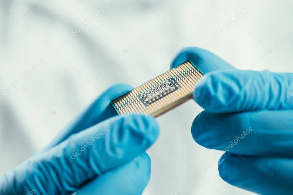 cropped view of engineer in rubber gloves holding computer microchip