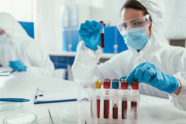 biochemist holding test tube with blood sample near colleague in laboratory clipart