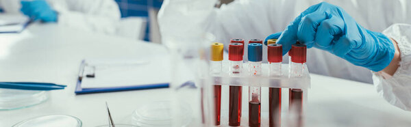 cropped view of biochemist taking test tube with blood sample, panoramic shot