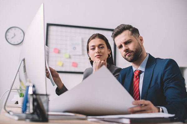 Selective focus of analytics working with papers at table in office 