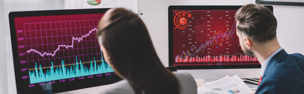 Selective focus of data analysts working with graphs on computer monitors in office, panoramic shot