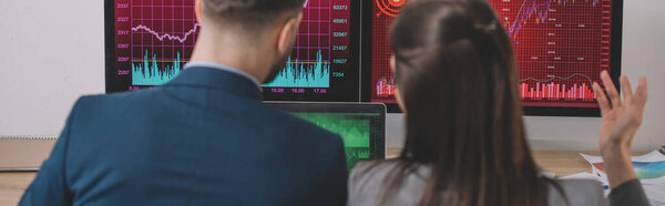 Back view of data analysts working on strategy of security with graphs on computer monitors, panoramic shot