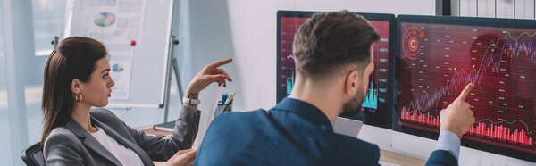 Data analysts pointing on charts on computer monitors while testing security software in office, panoramic shot 