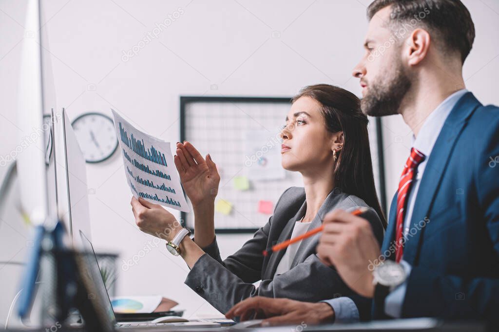 Side view of data analysts using charts while assessing risk in office 