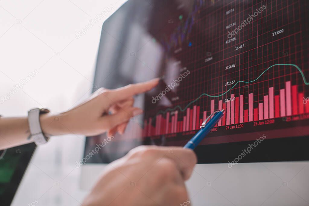 Selective focus of data analysts pointing on graphs on computer monitor while testing security of computer systems