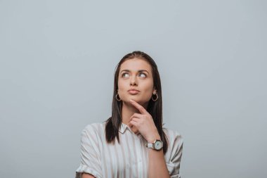 Dreamy girl with finger near chin looking up isolated on grey clipart