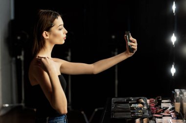 Fotoğraf stüdyosunda selfie çeken kadının yan görüntüsü. 