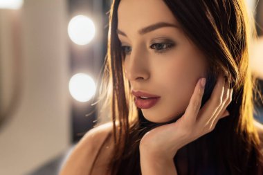 Çekici bir kadın fotoğraf stüdyosunda yüzüne dokunuyor. 