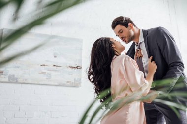 Yatak odasında erkek kravatı çeken iş adamı ve kız arkadaşın seçici odağı.