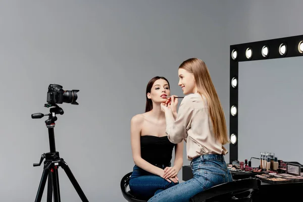 메이크업 아티스트가 매력적 모델의 입술에 립글로스를 적용하고 그레이의 디지털 카메라를 — 스톡 사진
