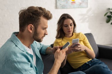Kanepede akıllı telefonlar kullanan bağımlı çiftlerin seçici odağı 