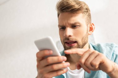 Akıllı telefonu işaret eden yakışıklı adamın seçici odağı 