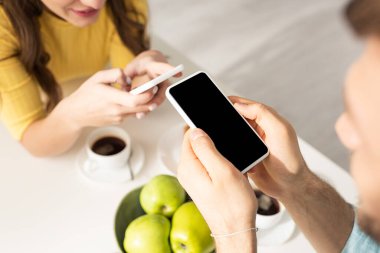 Kahvaltıda akıllı telefon kullanan genç çiftlerin seçici odağı 