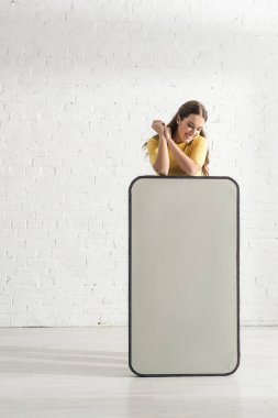 Akıllı telefonun büyük bir modelinin yanında dururken gülümseyen güzel kadın. 