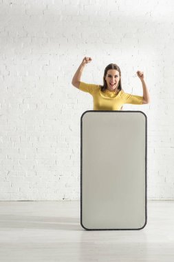 Mutlu kadın evdeki akıllı telefonun büyük bir modelinin yanında evet işareti yapıyor. 