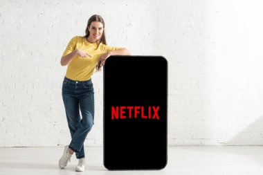 KYIV, UKRAINE - 21 Şubat 2020: Netflix uygulamalı akıllı telefon modelini gösteren gülen kız
