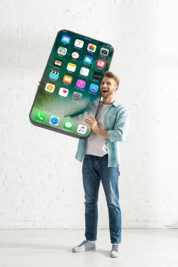 KYIV, UKRAINE - 21 Şubat 2020: iPhone ekranlı akıllı telefonun büyük modelini tutan mutlu adam 