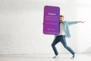 KYIV, UKRAINE - 21 Şubat 2020: Instagram uygulamalı dev akıllı telefon modelini elinde tutan pozitif adam