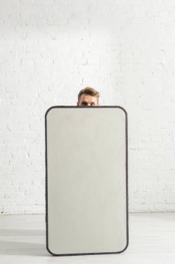 Evdeki akıllı telefonun büyük modelinin yanındaki kameraya bakan adam. 