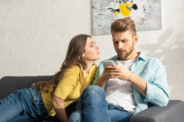 Menina Atraente Olhando Para Namorado Dependente Com Smartphone Sofá — Fotografia de Stock